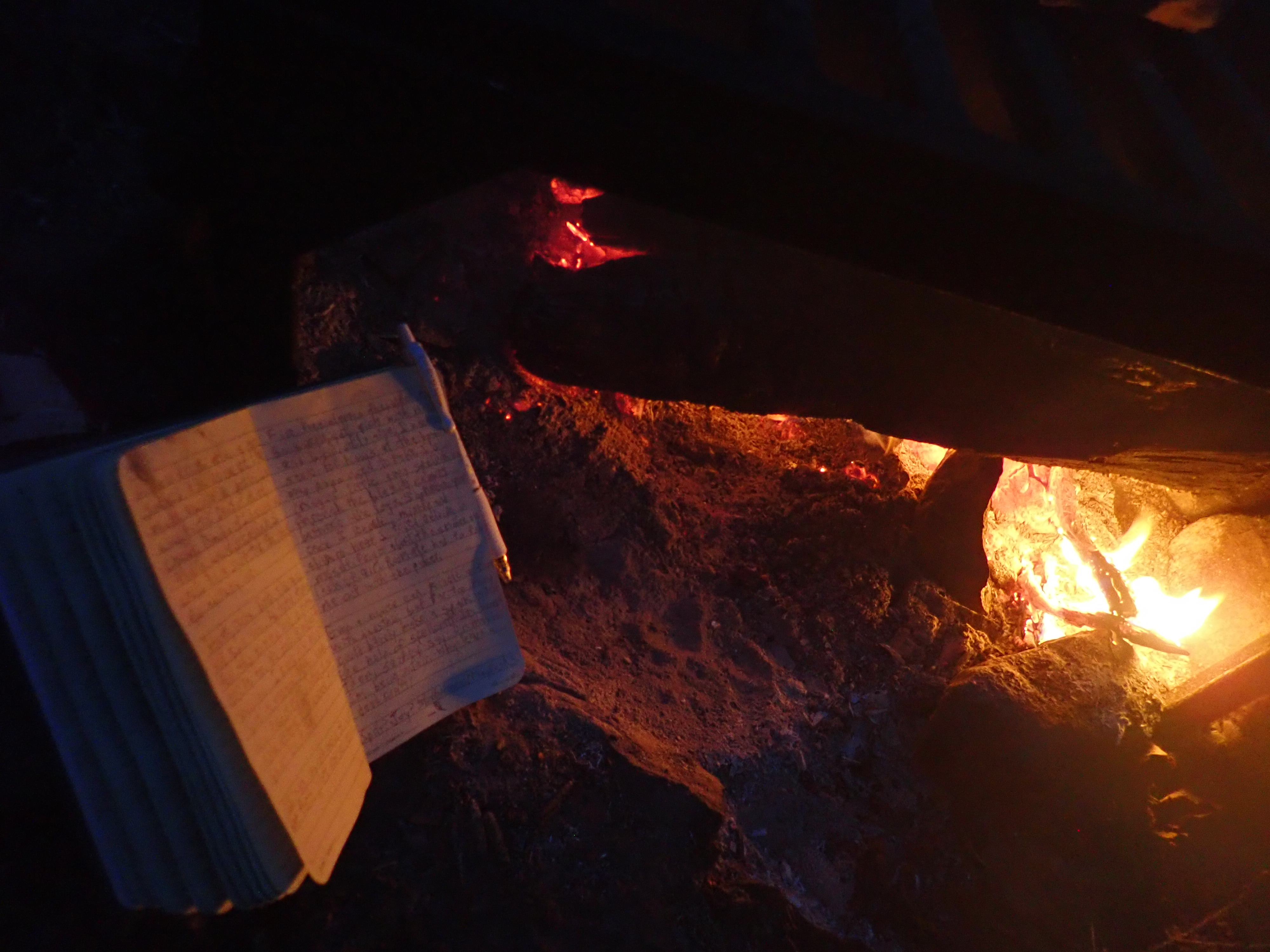 a picture of a notebook with a pen clipped to it resting against a stone, next to a campfire. written in the notebook are the above contents.